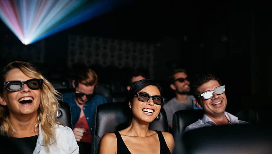 Freunde schauen sich 3D-Filme im Kino an und lachen